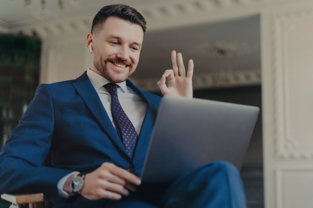 Happy successful businessman in blue navy elegant suit showing ok sign or satisfied gesture